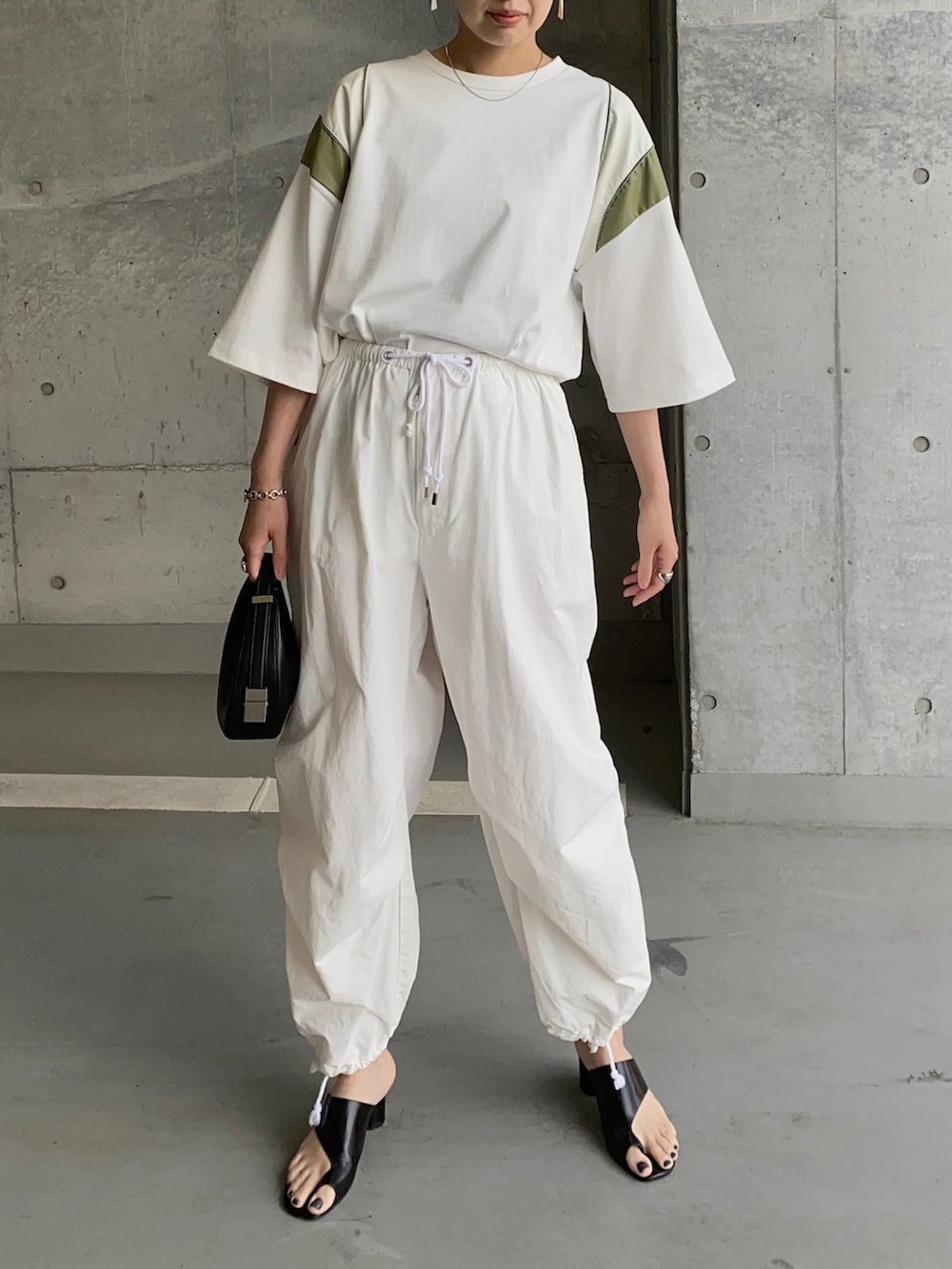 ホワイト系のTシャツ/カットソー、ホワイト系のその他パンツ、ブラック系のハンドバッグを着用したレディースの夏コーディネートの2枚目の写真