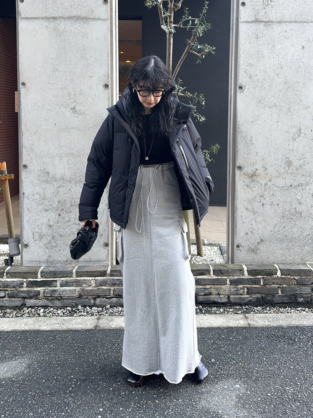 ブラック系のダウンジャケット/コート、グレー系のスカート、ブラック系のブーツを着用したレディースの冬コーディネートの2枚目の写真