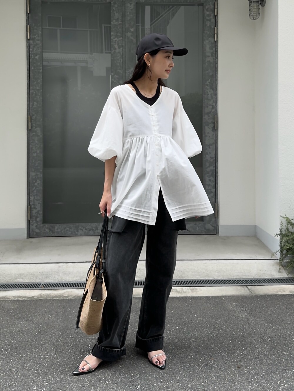 ホワイト系のチュニック、ブラック系のデニムパンツ、ベージュ系のトートバッグを着用したレディースの夏コーディネートの2枚目の写真