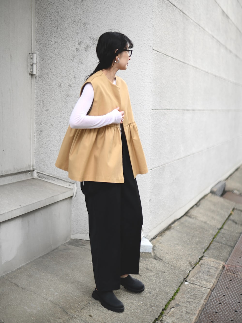 ベージュ系のベスト、ブラック系のショルダーバッグ、ブラック系のスラックスを着用したレディースの春コーディネートの5枚目の写真