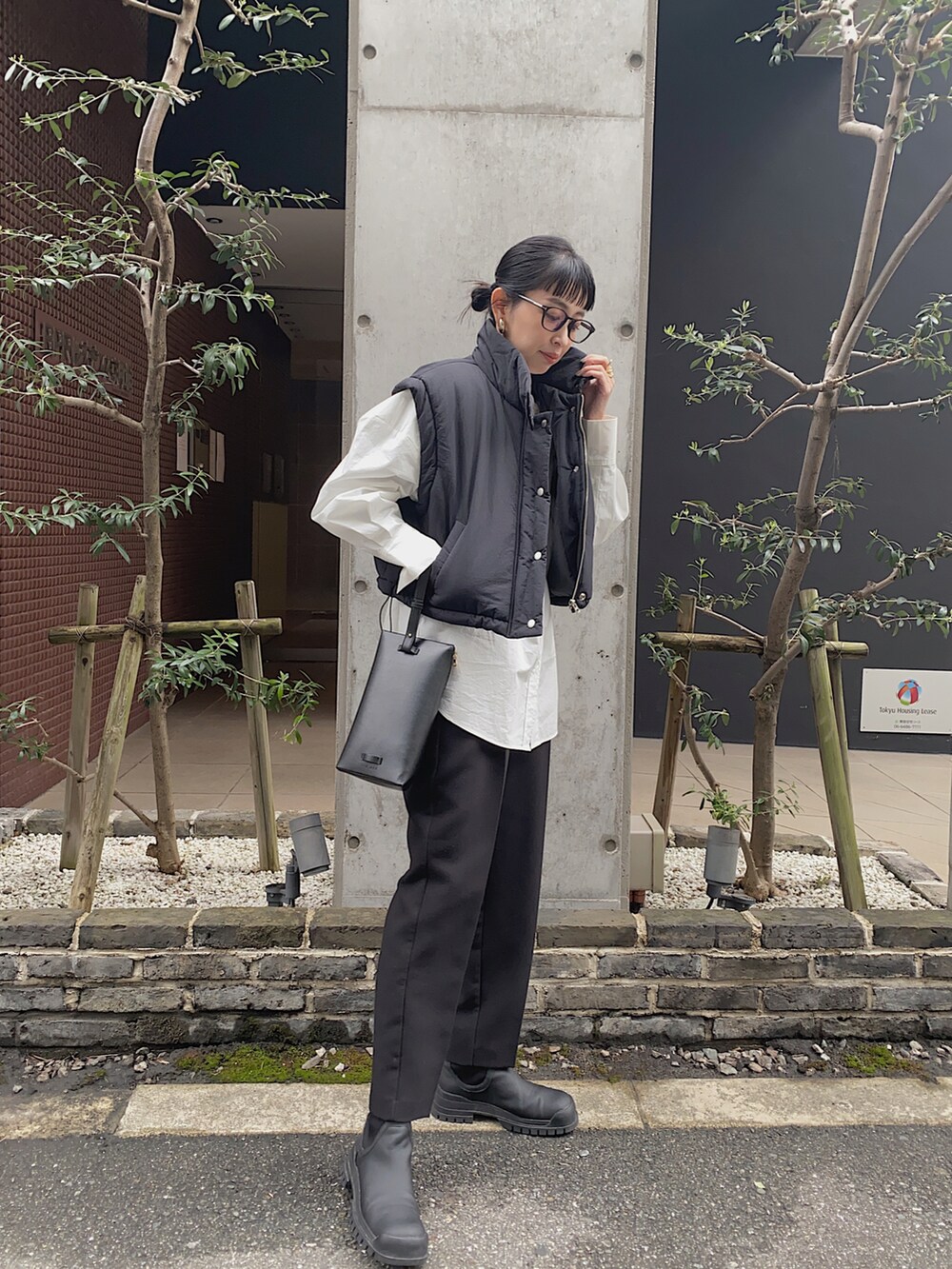 ブラック系のダウンベスト、ホワイト系のシャツ/ブラウス、ブラック系のメガネを着用したレディースの冬コーディネートの2枚目の写真