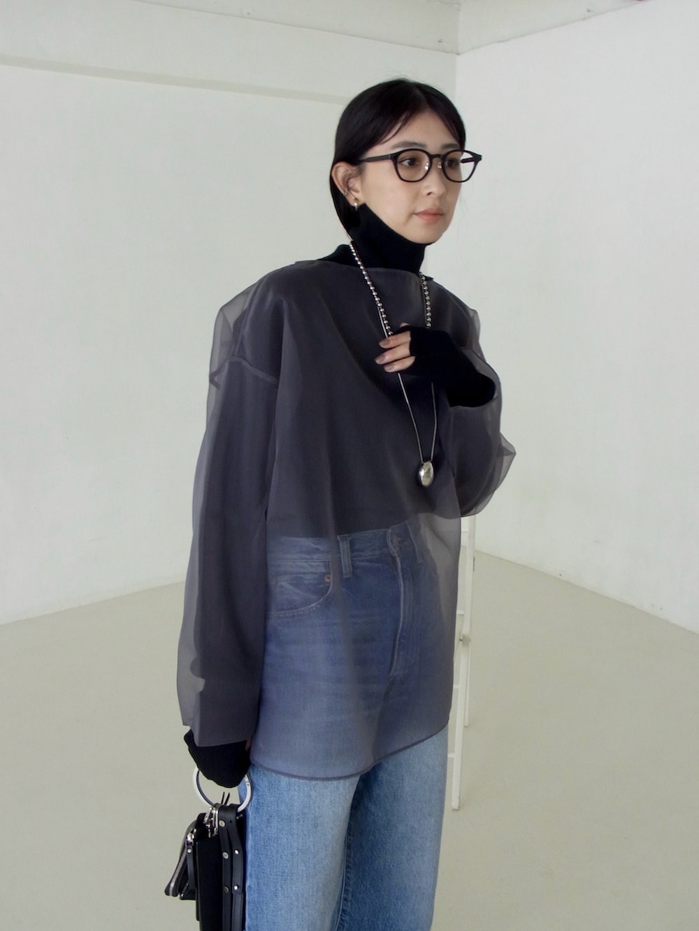 グレー系のシャツ/ブラウス、ブラック系のニット/セーター、ブラック系のショルダーバッグを着用したレディースの秋コーディネートの2枚目の写真