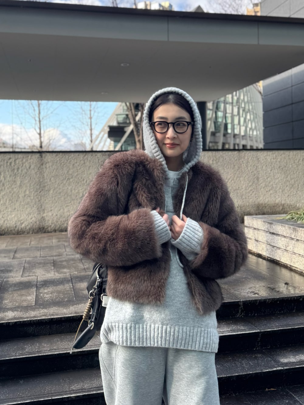ブラウン系のその他アウター、グレー系のニット/セーター、ブラック系のキーホルダーを着用したレディースの冬コーディネートの3枚目の写真