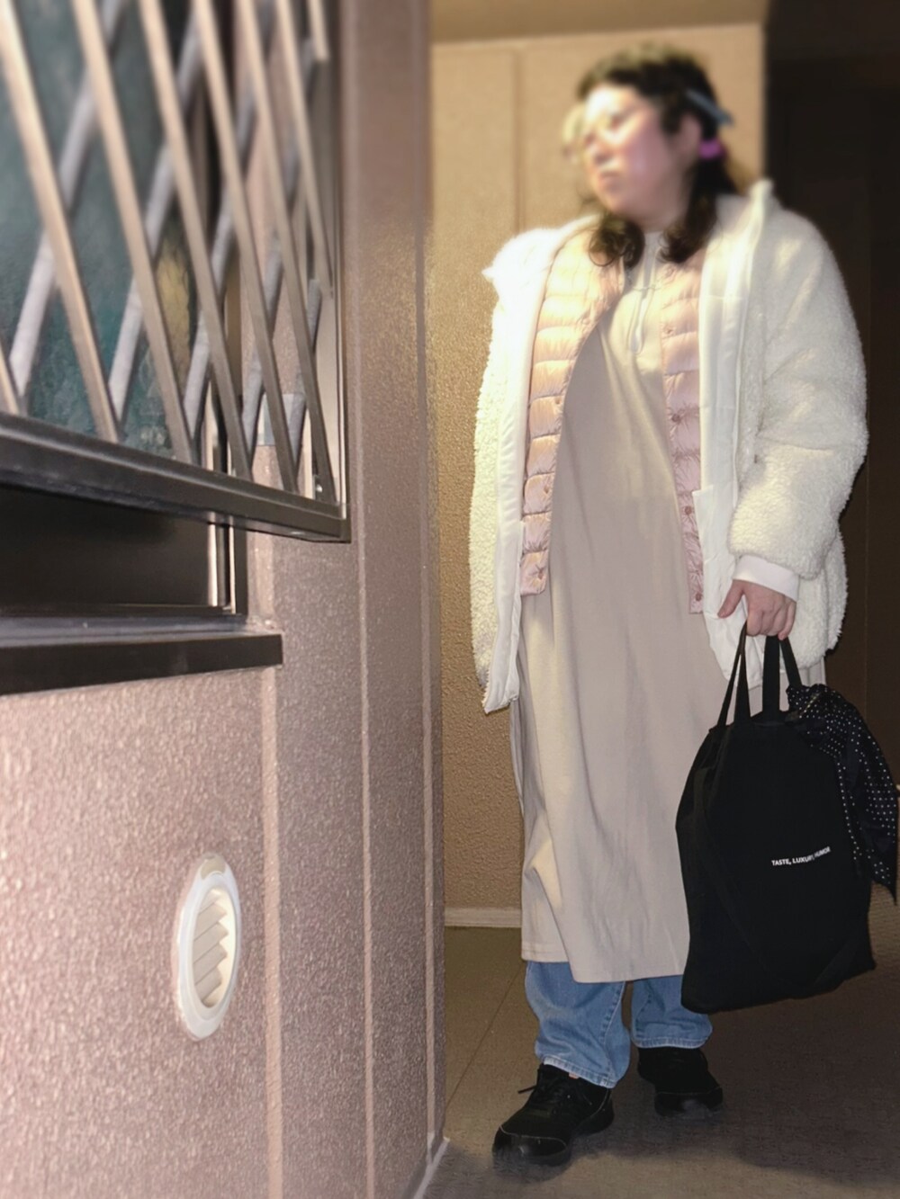 ホワイト系のブルゾン、ピンク系のダウンジャケット/コート、ベージュ系のジャンパースカートを着用したレディースの春コーディネートの2枚目の写真