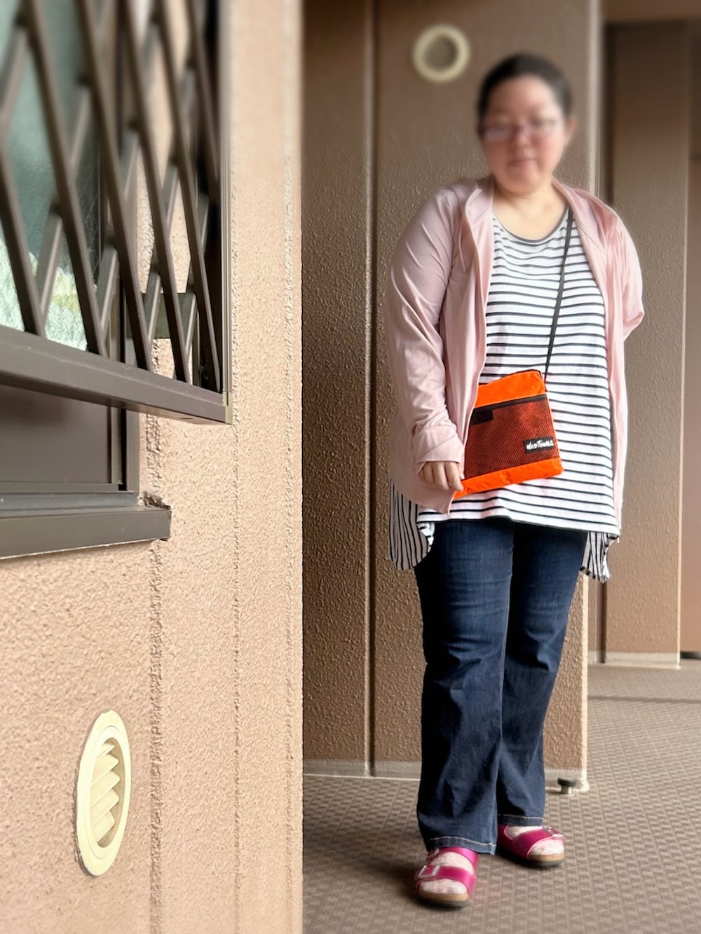 ホワイト系のタンクトップ、オレンジ系のショルダーバッグ、ブルー系のデニムパンツを着用したレディースの夏コーディネートの3枚目の写真