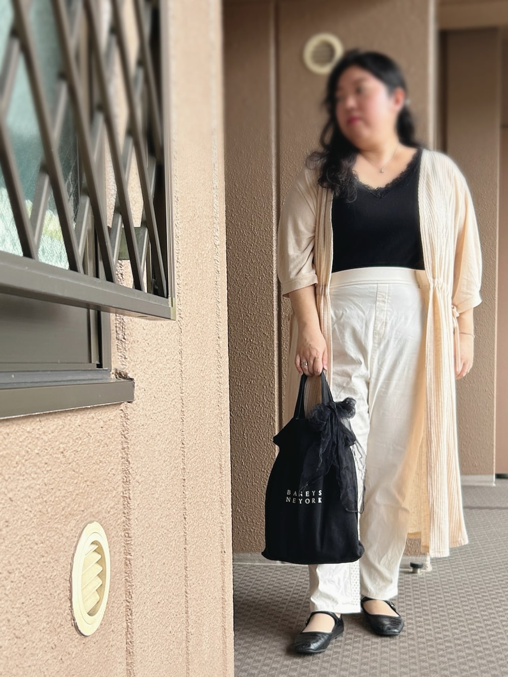 ベージュ系のカーディガン/ボレロ、ブラック系のタンクトップ、ホワイト系のパンツを着用したレディースの秋コーディネートの2枚目の写真