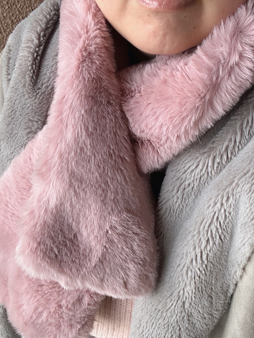 ピンク系のニット/セーター、ブラウン系のスカート、グレー系のムートンコートを着用したレディースの冬コーディネートの2枚目の写真