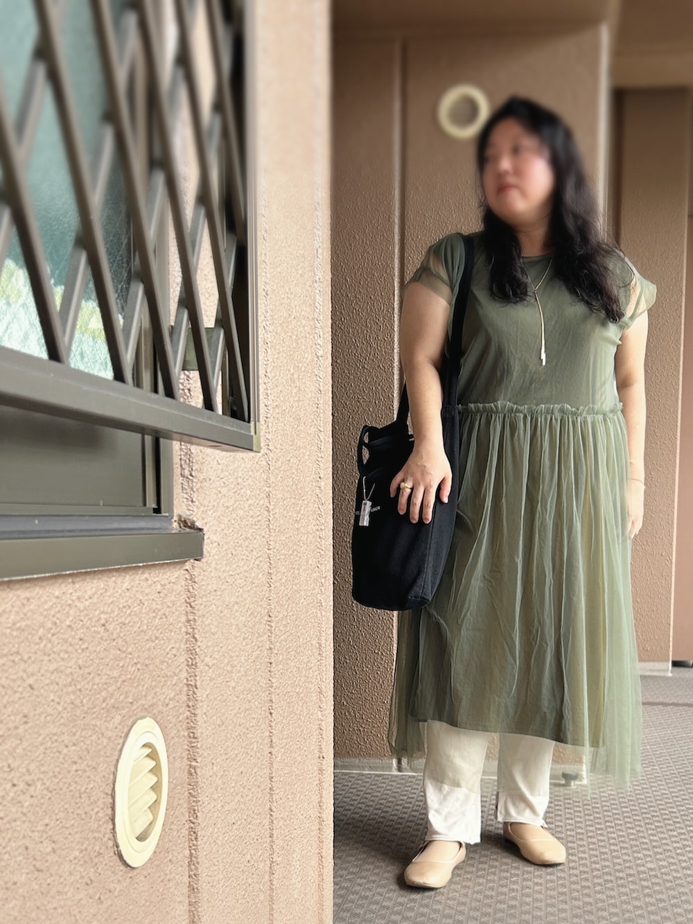 グリーン系のワンピース、ベージュ系のバレエシューズ、ブラック系のトートバッグを着用したレディースの秋コーディネートの2枚目の写真