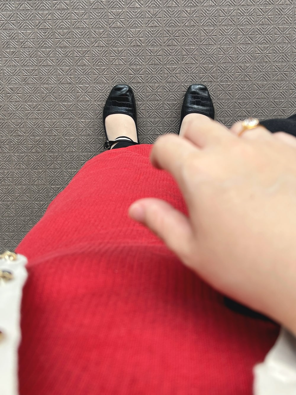 レッド系のワンピース、ベージュ系のカーディガン/ボレロ、ブラック系のトートバッグを着用したレディースの秋コーディネートの3枚目の写真