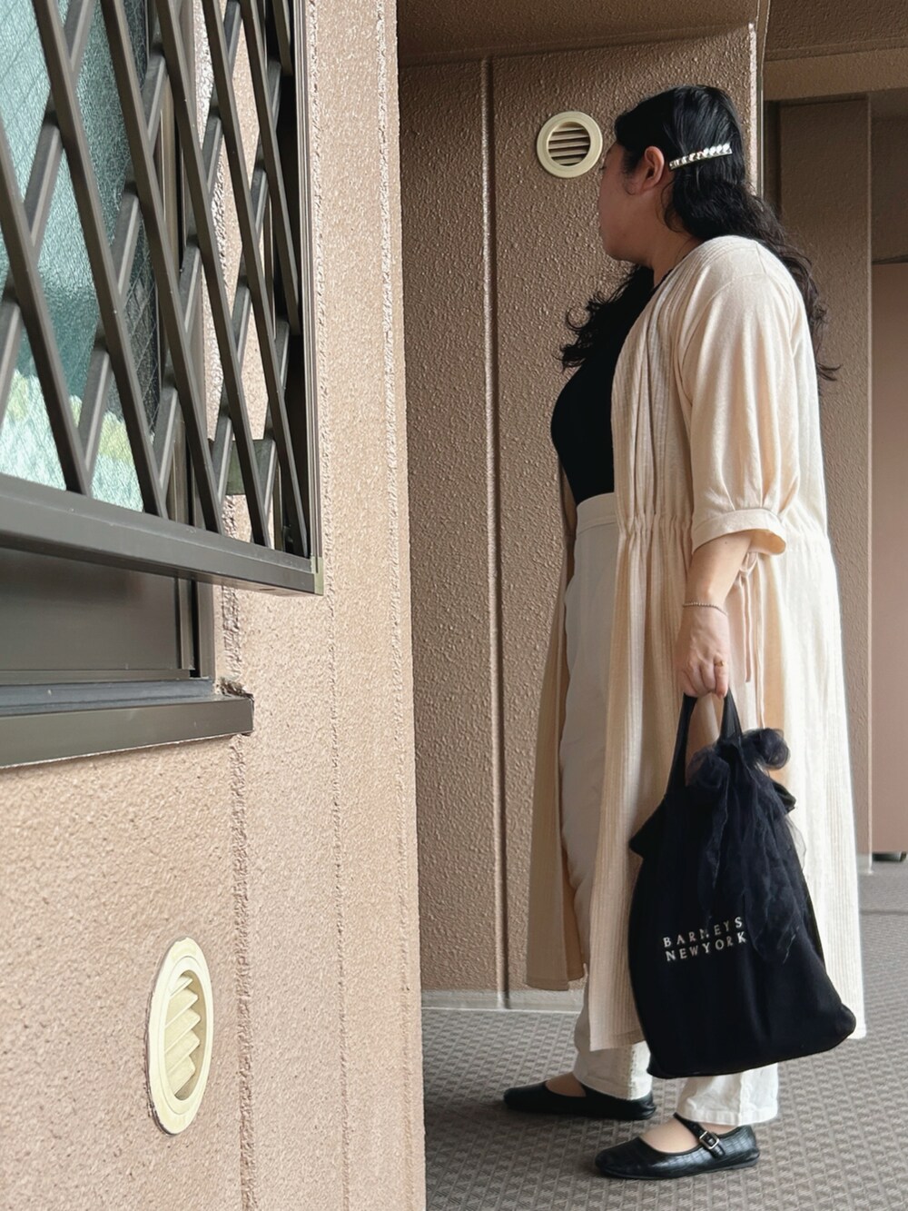 ベージュ系のカーディガン/ボレロ、ブラック系のタンクトップ、ホワイト系のパンツを着用したレディースの秋コーディネートの3枚目の写真