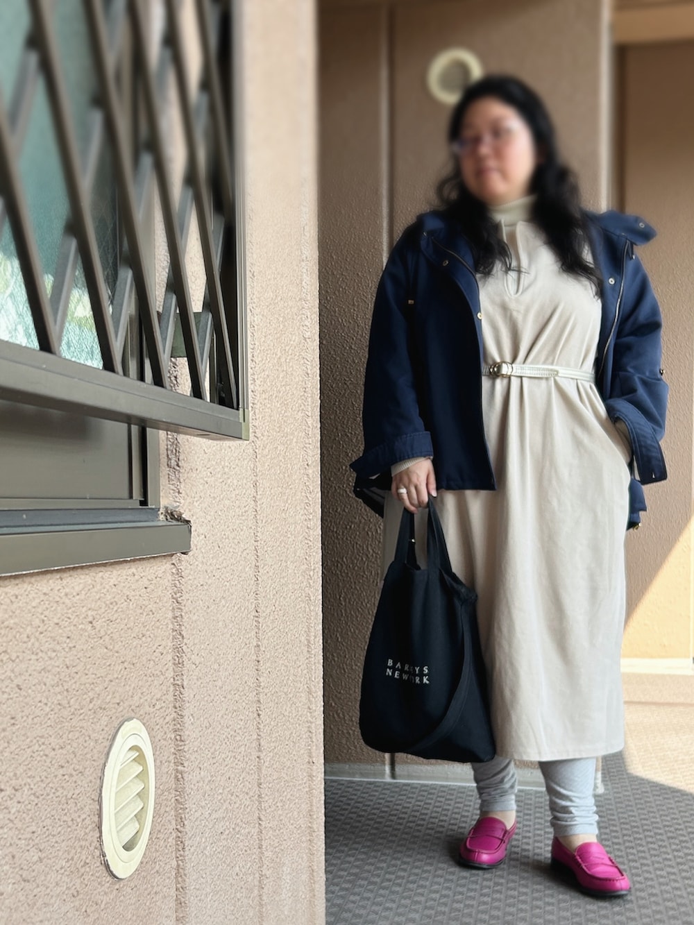 ベージュ系のジャンパースカート、ホワイト系のニット/セーター、ブルー系のマウンテンパーカーを着用したレディースの夏コーディネートの2枚目の写真