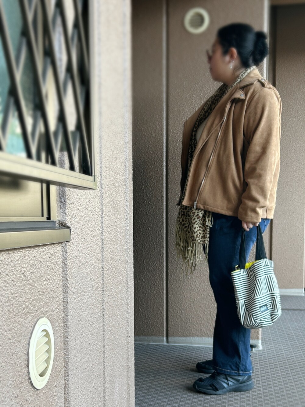 ブラウン系のライダースジャケット、ベージュ系のニット/セーター、ブルー系のデニムパンツを着用したレディースの冬コーディネートの3枚目の写真