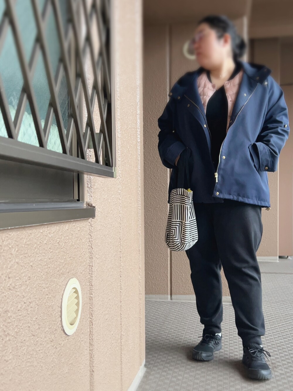 ブラック系のその他パンツ、ブラック系のニット/セーター、ピンク系のダウンジャケット/コートを着用したレディースの冬コーディネートの3枚目の写真