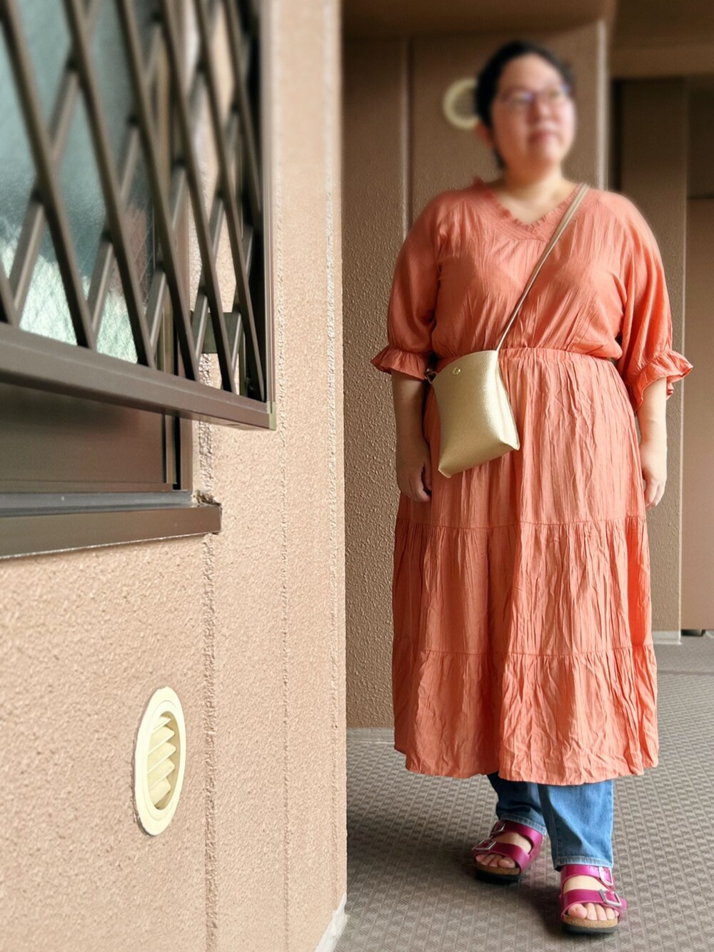 オレンジ系のワンピース、ゴールド系のショルダーバッグ、その他のパンツを着用したレディースの夏コーディネートの2枚目の写真