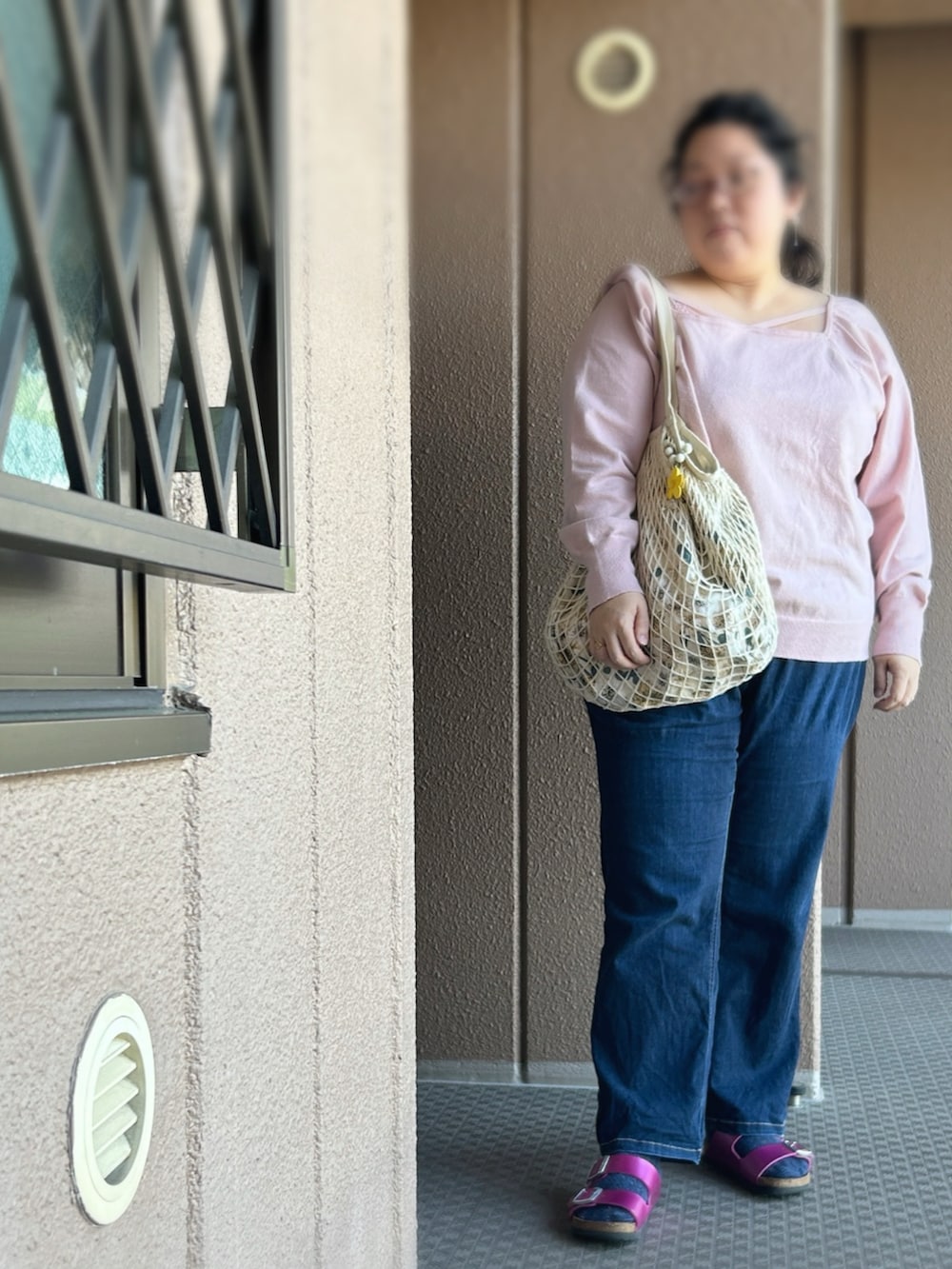 ピンク系のニット/セーター、ブルー系のデニムパンツ、ピンク系のサンダルを着用したレディースの夏コーディネートの3枚目の写真