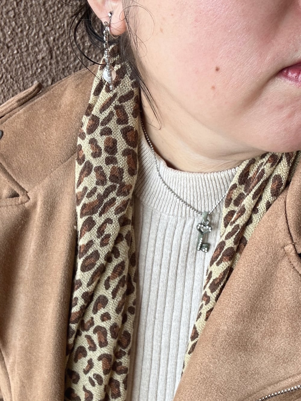 ブラウン系のライダースジャケット、ベージュ系のニット/セーター、ブルー系のデニムパンツを着用したレディースの冬コーディネートの4枚目の写真