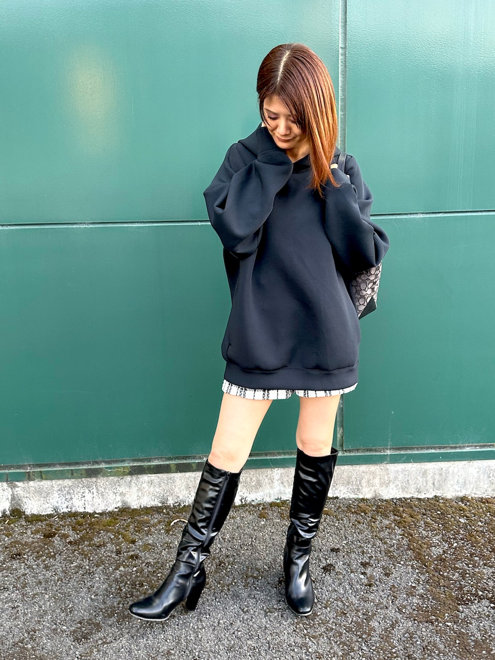 ブラック系のパーカー、ホワイト系のパンツ、ブラック系のブーツを着用したレディースの秋コーディネートの2枚目の写真