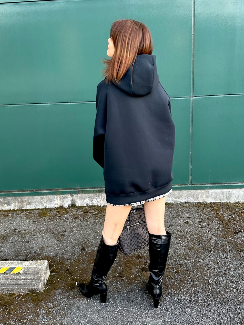 ブラック系のパーカー、ホワイト系のパンツ、ブラック系のブーツを着用したレディースの秋コーディネートの5枚目の写真