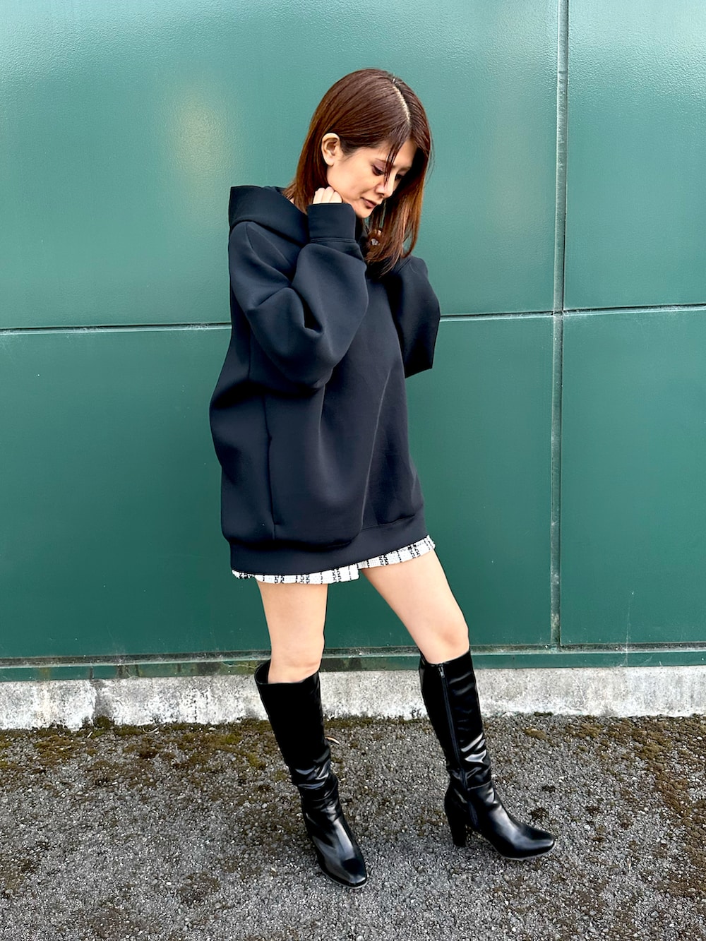 ブラック系のパーカー、ホワイト系のパンツ、ブラック系のブーツを着用したレディースの秋コーディネートの3枚目の写真