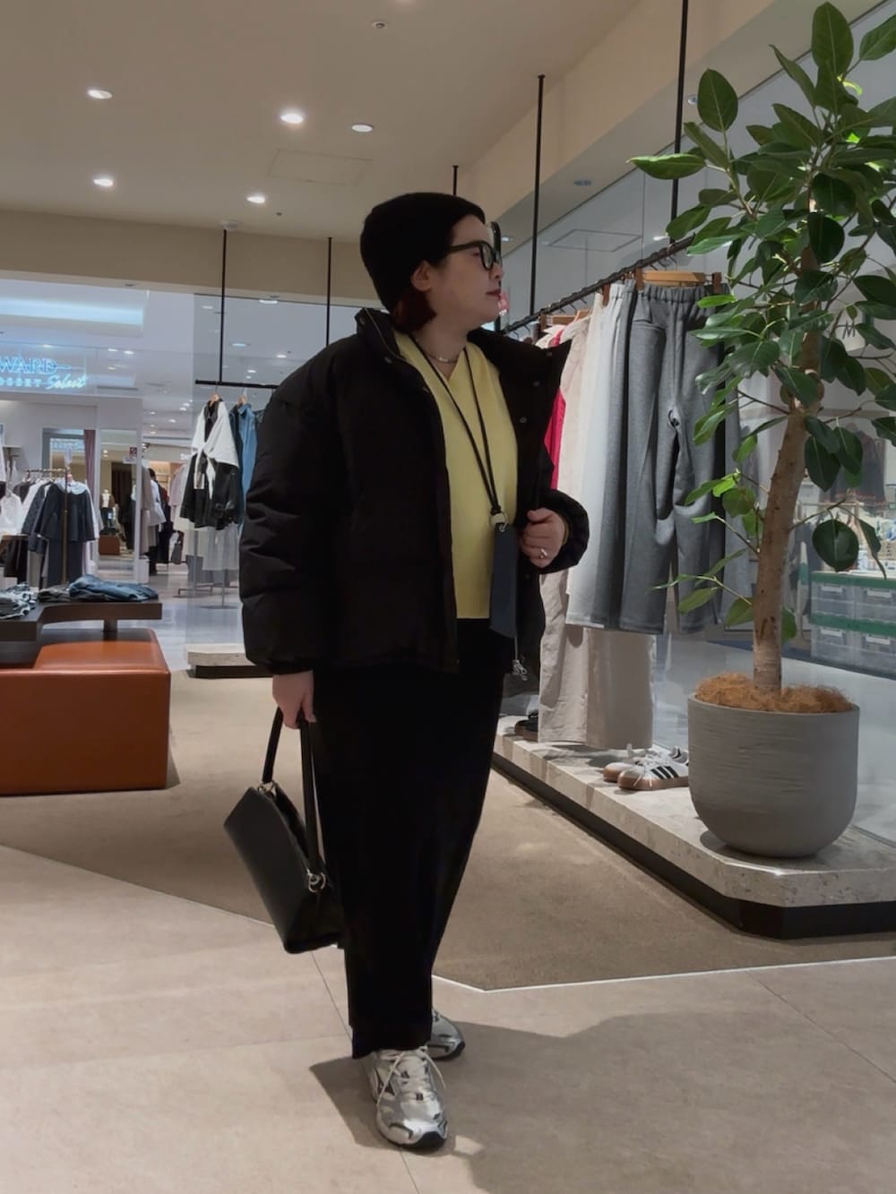 ブラック系のダウンジャケット/コート、イエロー系のニット/セーター、ブラック系のスカートを着用したレディースの冬コーディネートの2枚目の写真