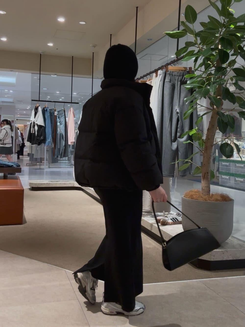 ブラック系のダウンジャケット/コート、イエロー系のニット/セーター、ブラック系のスカートを着用したレディースの冬コーディネートの3枚目の写真