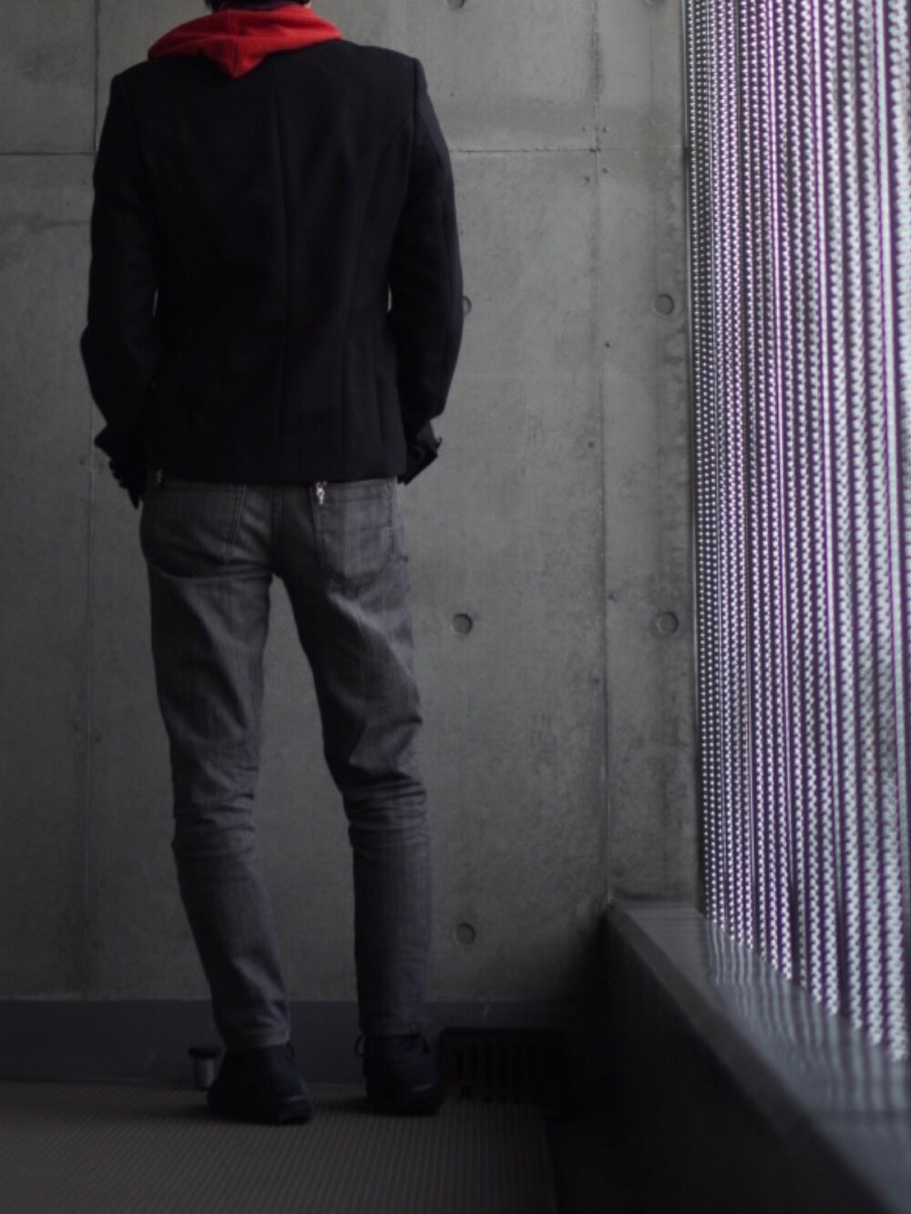 ブラック系のスニーカー、ブラック系のデニムパンツ、レッド系のパーカーを着用したメンズの冬コーディネートの3枚目の写真