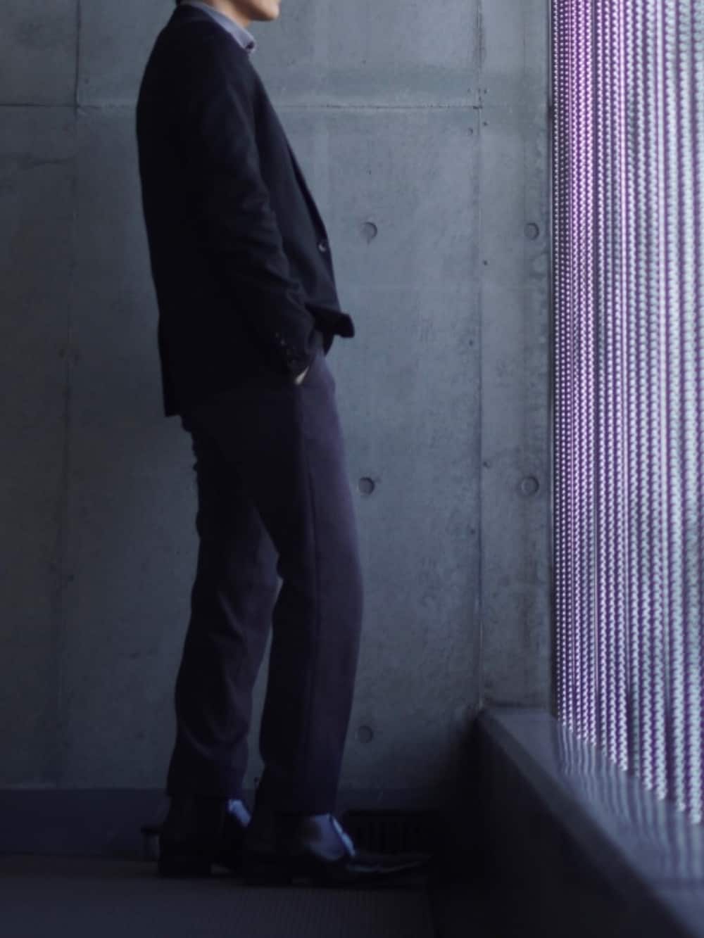 グレー系のスラックス、ブラック系のブーツ、ブルー系のニット/セーターを着用したメンズの冬コーディネートの2枚目の写真