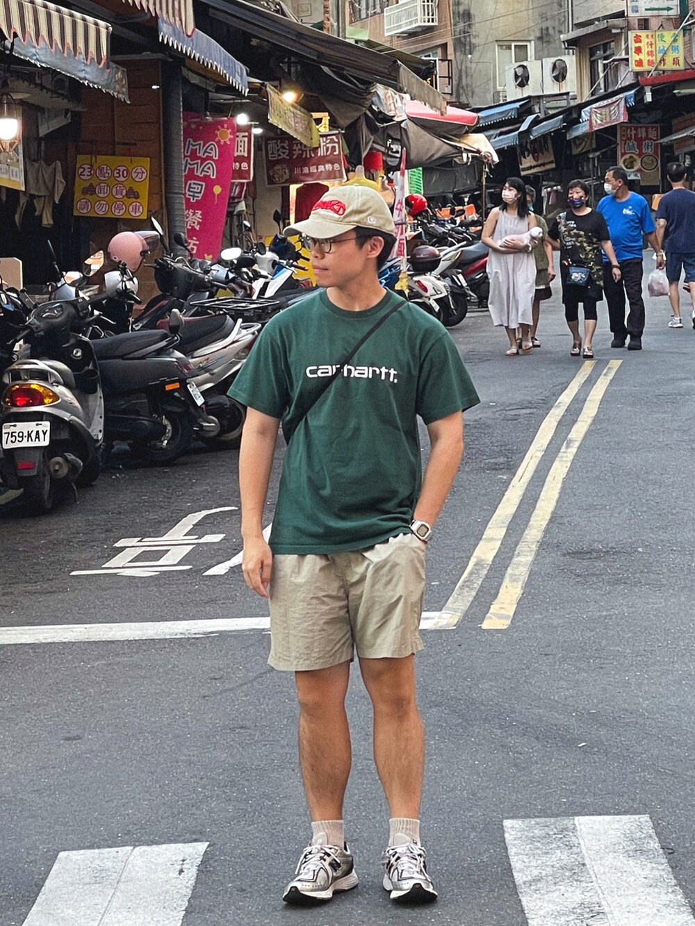 グリーン系のTシャツ/カットソー、ベージュ系のパンツ、シルバー系のスニーカーを着用したメンズの夏コーディネートの2枚目の写真