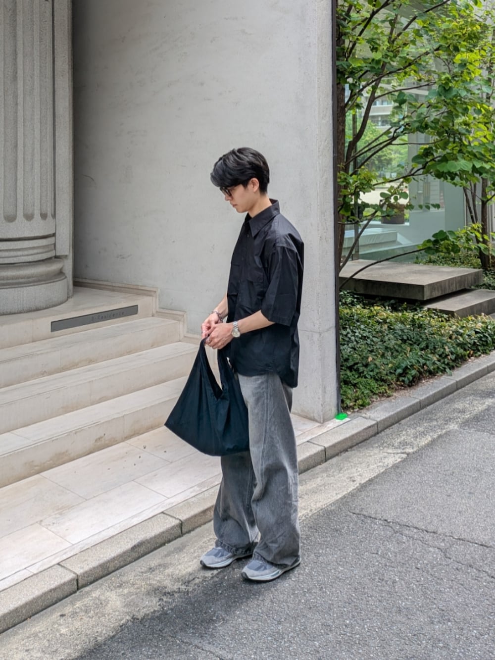 グレー系のデニムパンツ、グレー系のスニーカー、ブラック系のトートバッグを着用したメンズの夏コーディネートの2枚目の写真