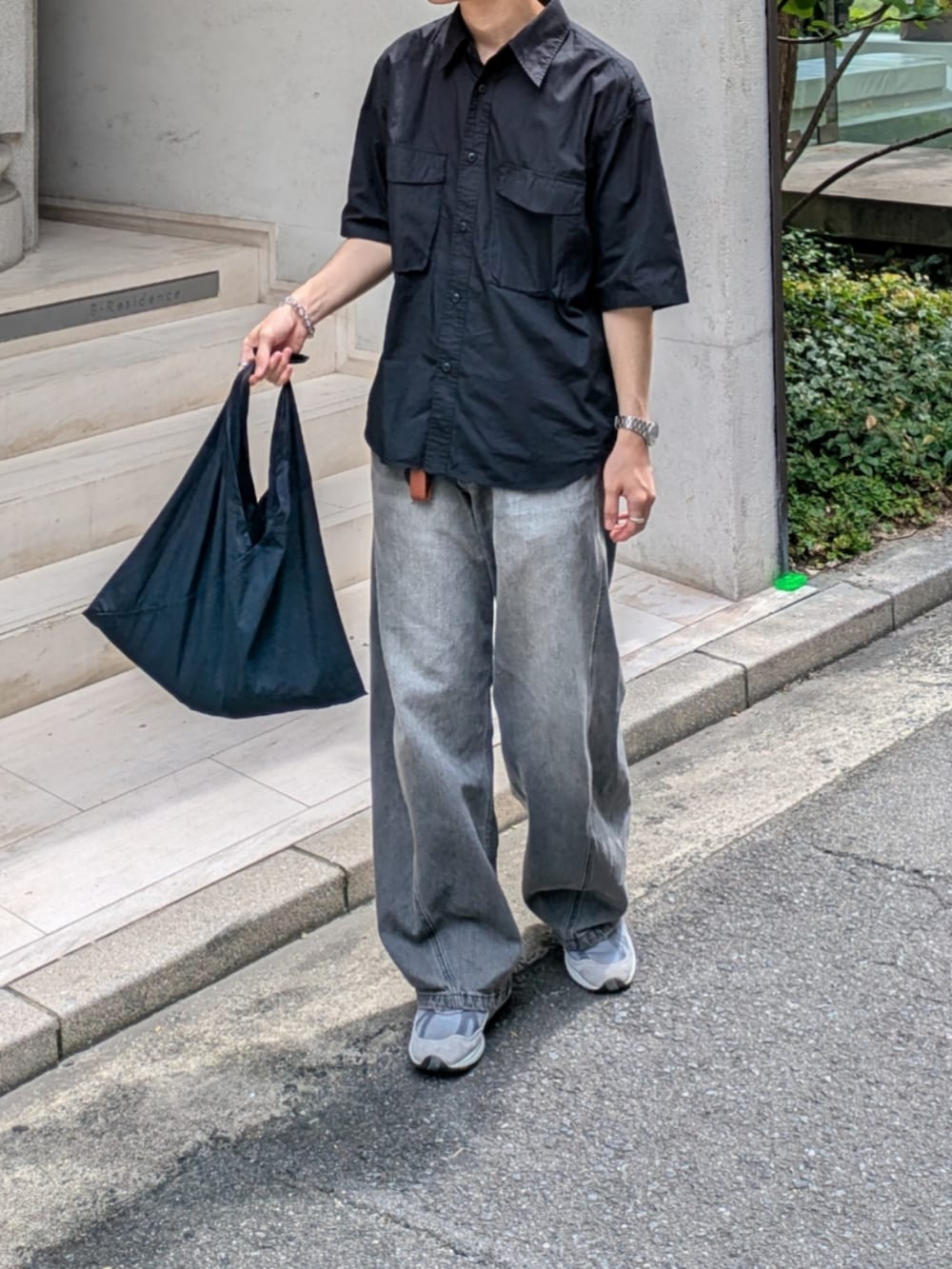 グレー系のデニムパンツ、グレー系のスニーカー、ブラック系のトートバッグを着用したメンズの夏コーディネートの3枚目の写真
