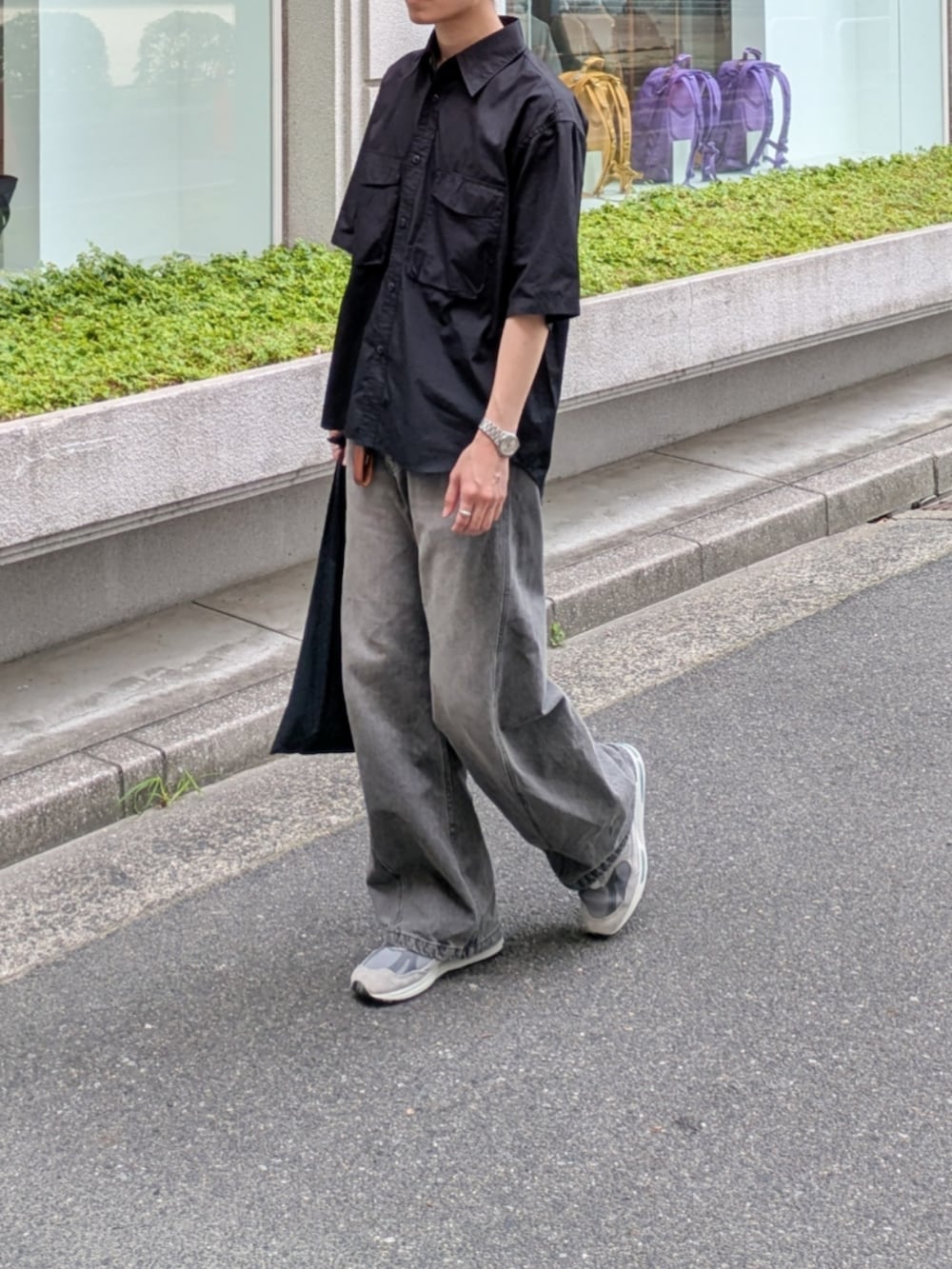 グレー系のデニムパンツ、グレー系のスニーカー、ブラック系のトートバッグを着用したメンズの夏コーディネートの4枚目の写真