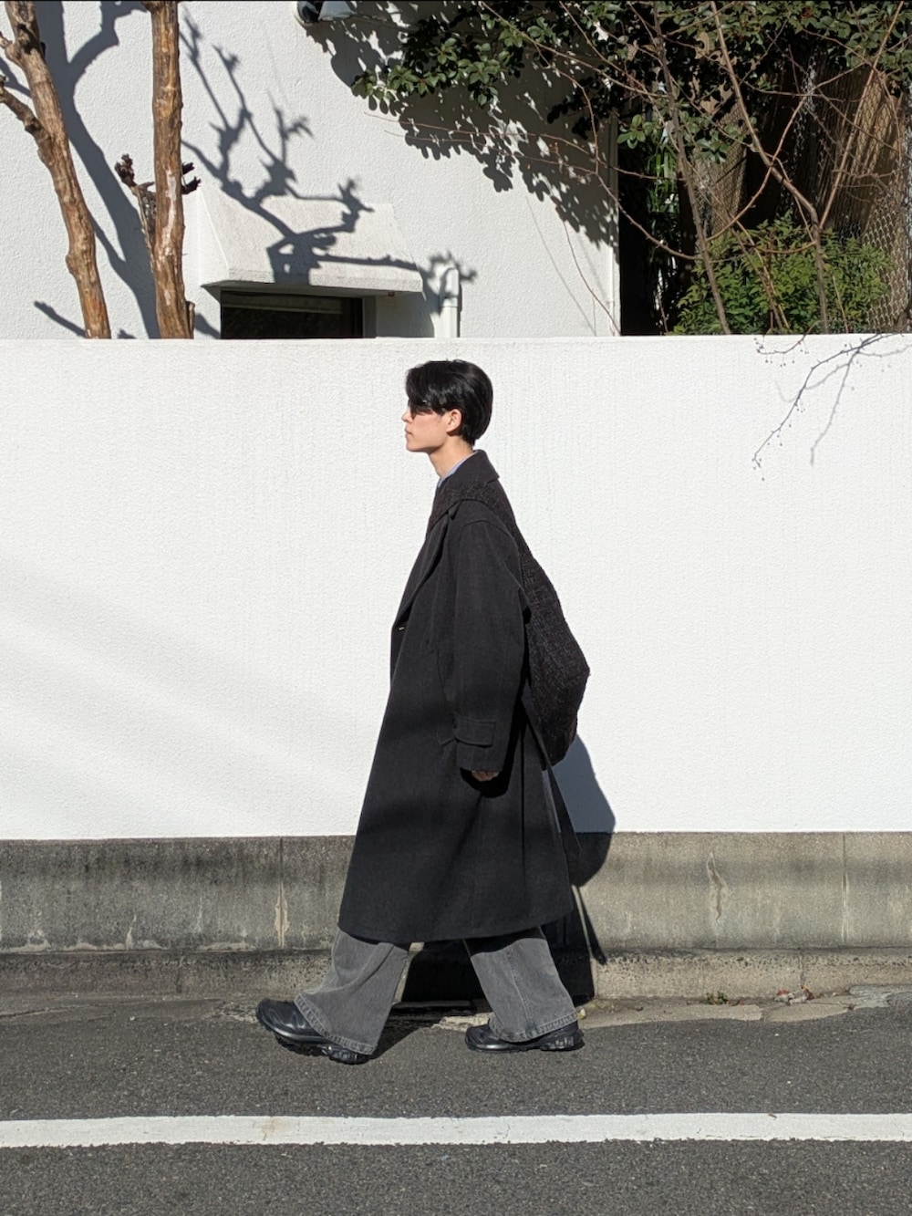 グレー系のその他アウター、ブラック系のショルダーバッグ、グレー系のデニムパンツを着用したメンズの冬コーディネートの2枚目の写真