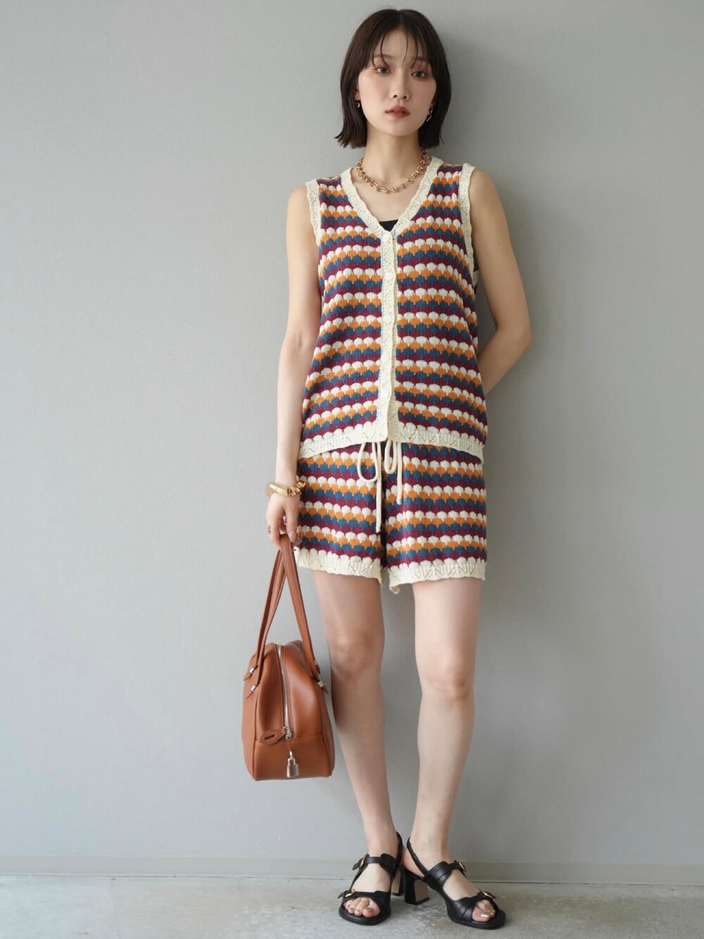 オレンジ系のセットアップを着用したレディースの夏コーディネートの2枚目の写真