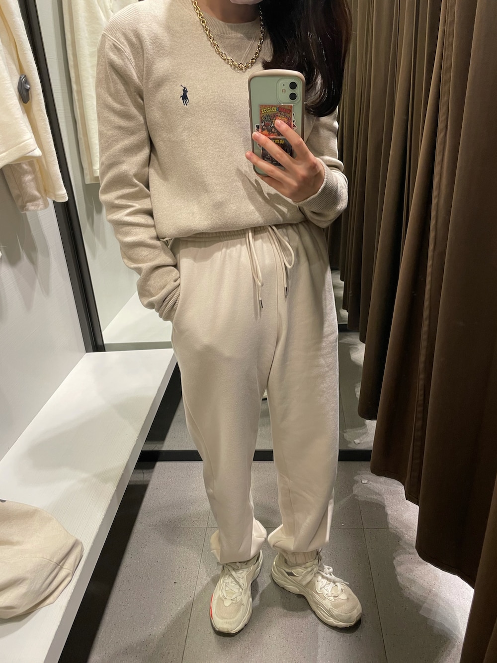 ホワイト系のスウェットパンツ、ベージュ系のニット/セーター、ホワイト系のスニーカーを着用したレディースの秋コーディネートの2枚目の写真