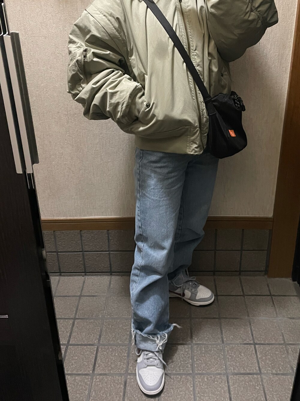 グリーン系のブルゾン、ブルー系のデニムパンツ、グレー系のスニーカーを着用したレディースの冬コーディネートの2枚目の写真