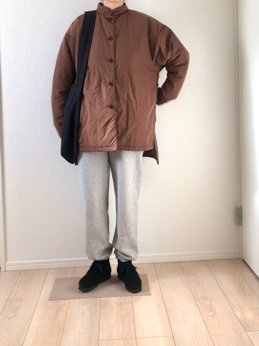 ブラウン系のダウンジャケット/コート、ブラック系のショルダーバッグ、グレー系のスウェットパンツを着用したレディースの冬コーディネートの2枚目の写真