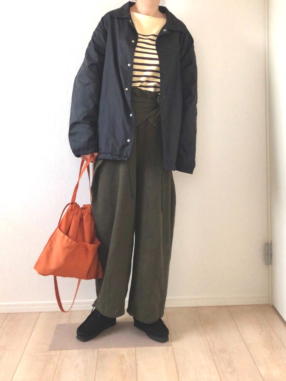 ブラック系のナイロンジャケット、イエロー系のTシャツ/カットソー、オレンジ系のショルダーバッグを着用したレディースの冬コーディネートの2枚目の写真