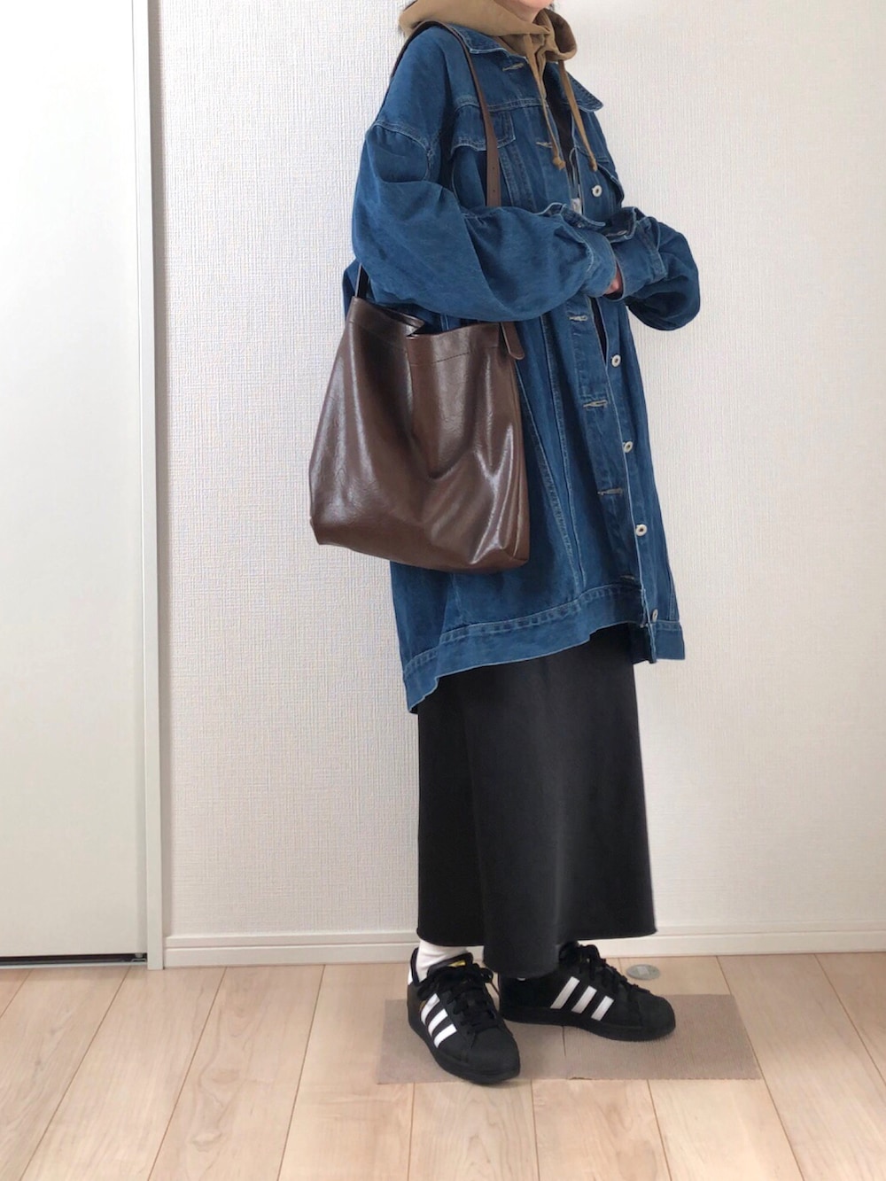 ブルー系のデニムジャケット、ブラック系のTシャツ/カットソー、ブラウン系のショルダーバッグを着用したレディースの秋コーディネートの2枚目の写真