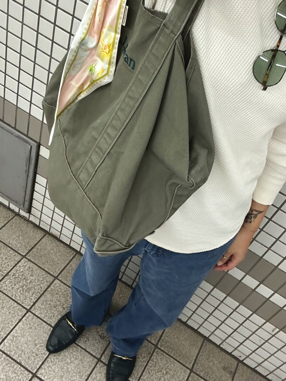 グリーン系のトートバッグ、グリーン系のローファー、ホワイト系のTシャツ/カットソーを着用したレディースの秋コーディネートの2枚目の写真
