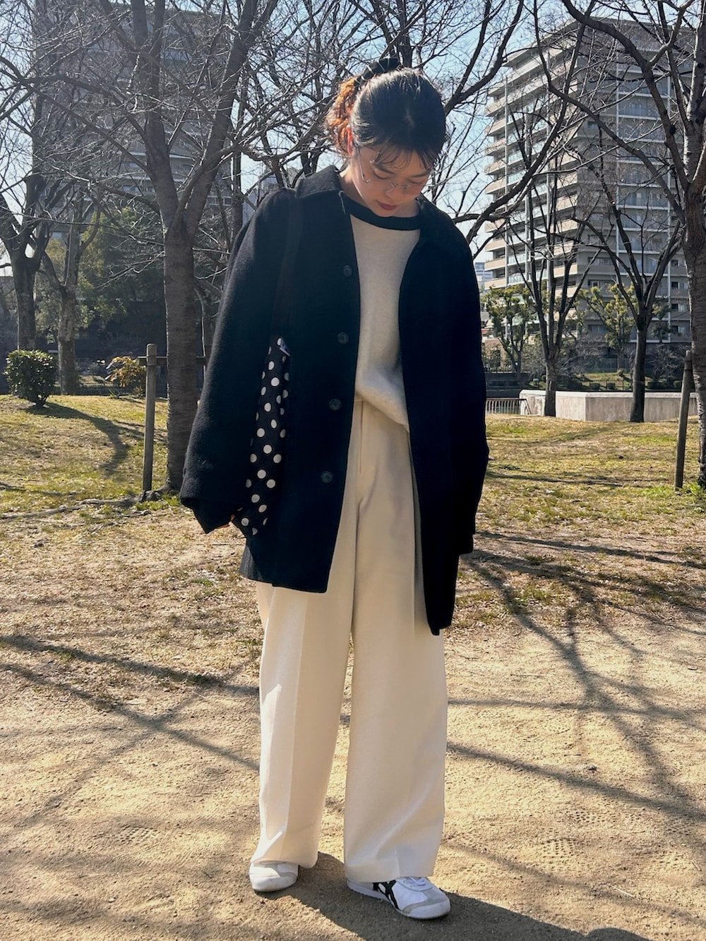 ホワイト系のスニーカー、ホワイト系のスラックス、ホワイト系のニット/セーターを着用したレディースの春コーディネートの2枚目の写真