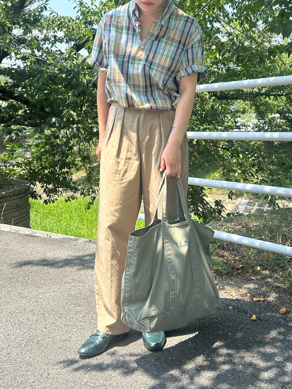 グリーン系のローファー、グリーン系のトートバッグ、ブルー系のシャツ/ブラウスを着用したレディースの夏コーディネートの2枚目の写真