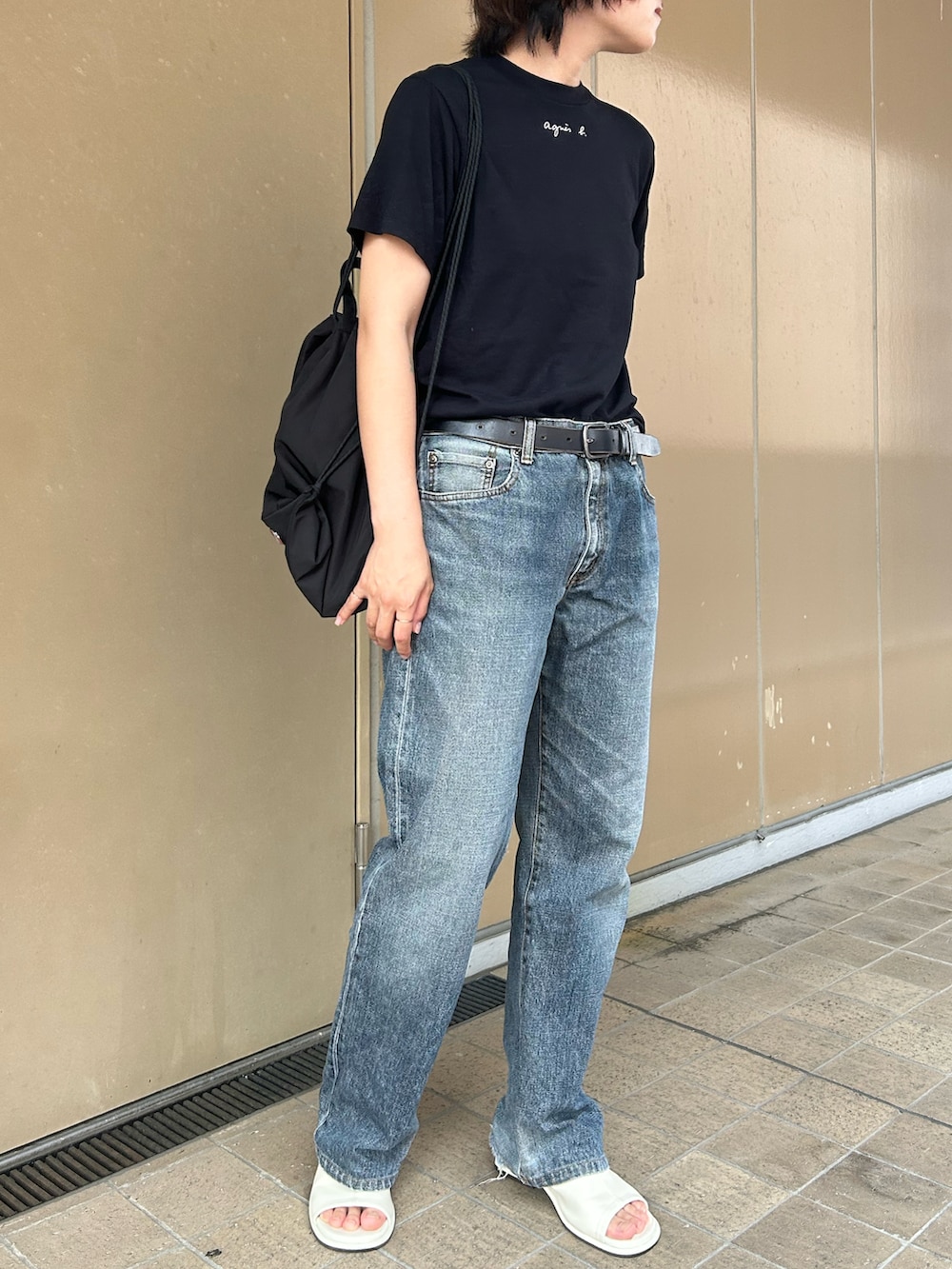 ブラック系のバックパック/リュック、ブラック系のTシャツ/カットソー、ホワイト系のサンダルを着用したレディースの夏コーディネートの2枚目の写真