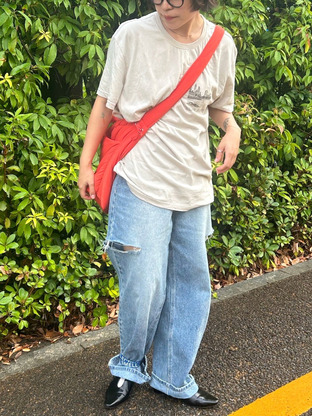 ブルー系のデニムパンツ、オレンジ系のトートバッグ、ブラック系のパンプスを着用したレディースの夏コーディネートの2枚目の写真