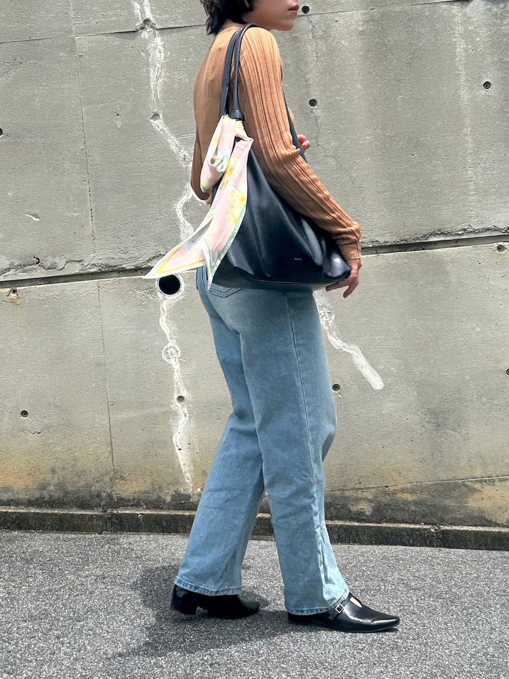 ブラック系のパンプス、ベージュ系のTシャツ/カットソー、ブルー系のデニムパンツを着用したレディースの夏コーディネートの2枚目の写真
