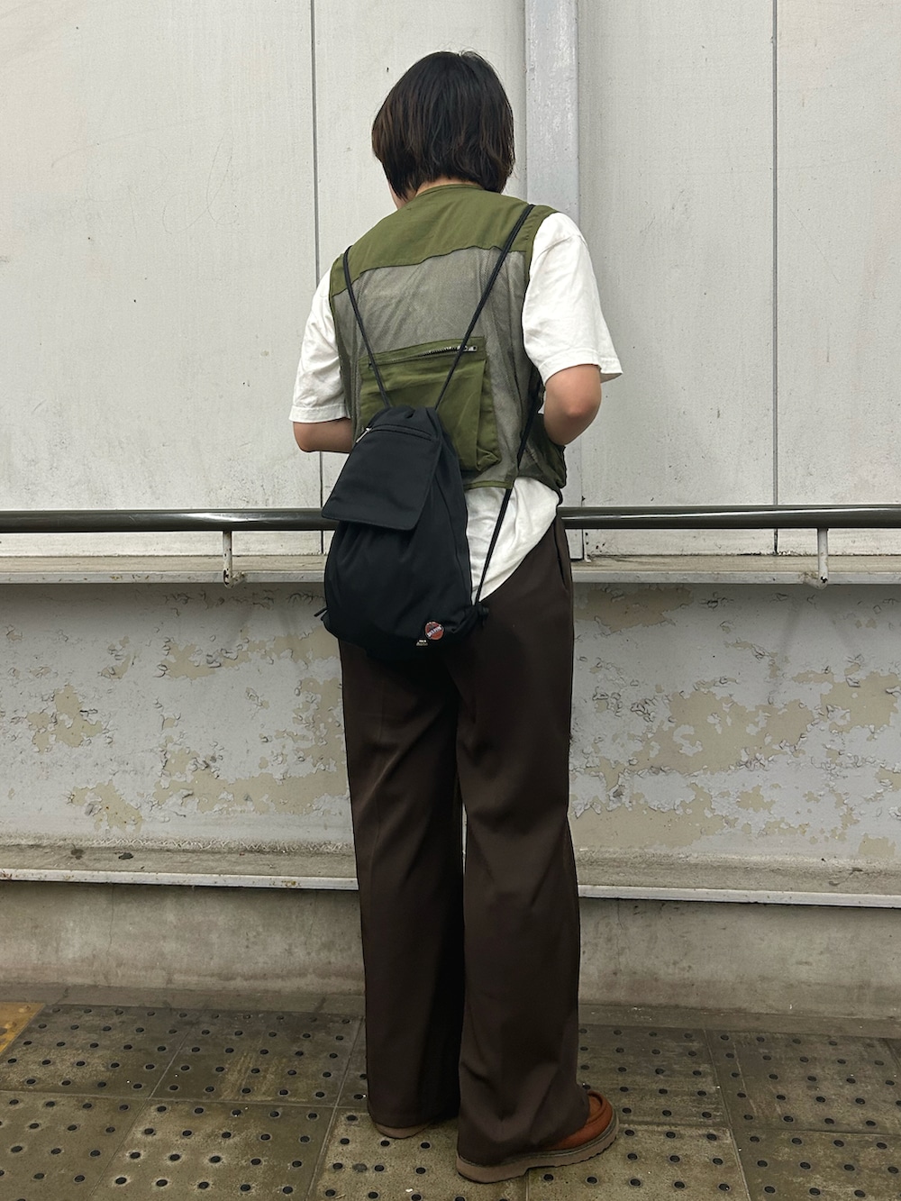 ブラック系のバックパック/リュック、グリーン系のベスト、ホワイト系のTシャツ/カットソーを着用したレディースの夏コーディネートの2枚目の写真