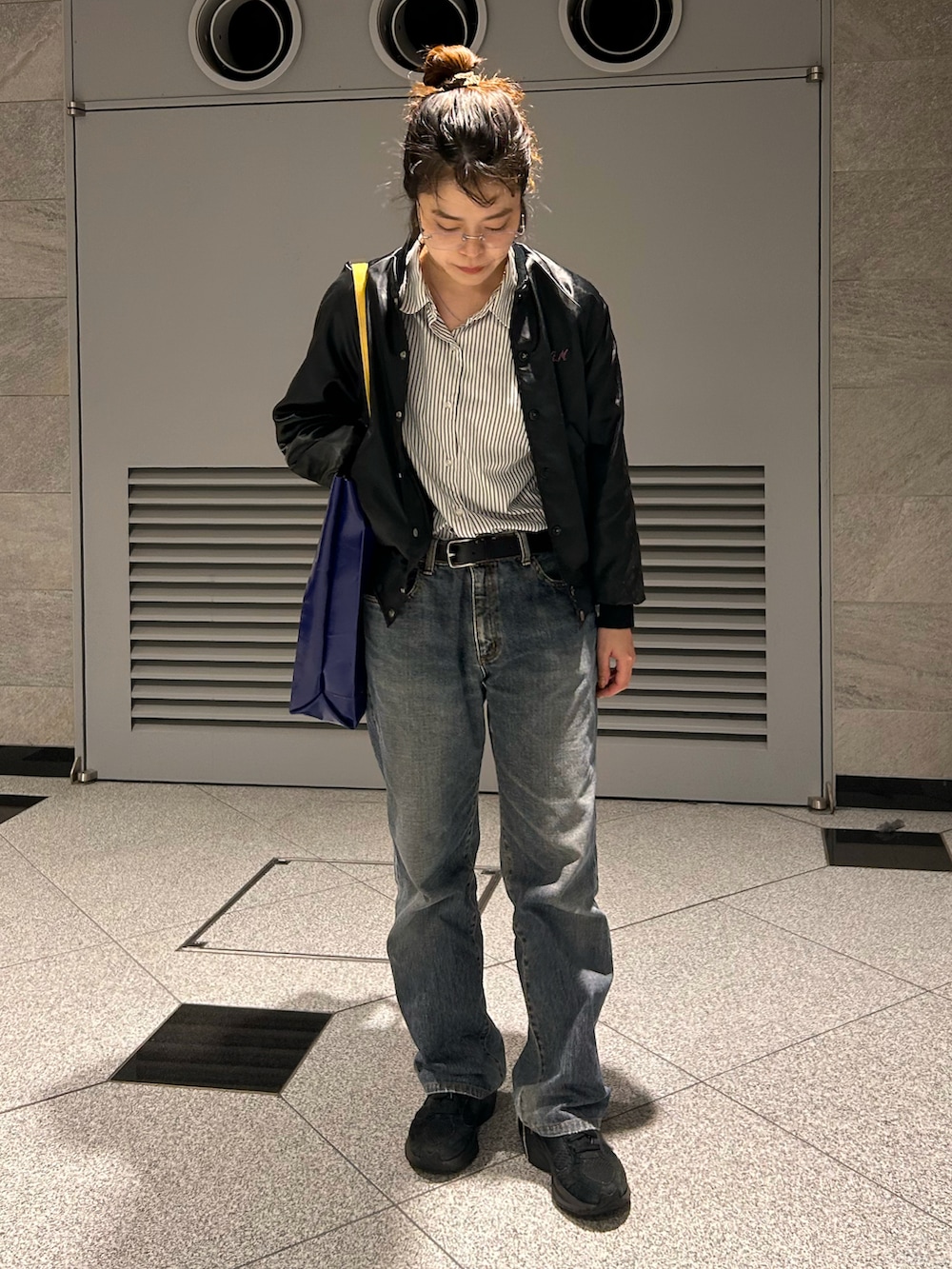 ブラック系のスニーカー、ブラック系のブルゾン、ブラック系のデニムパンツを着用したレディースの春コーディネートの2枚目の写真