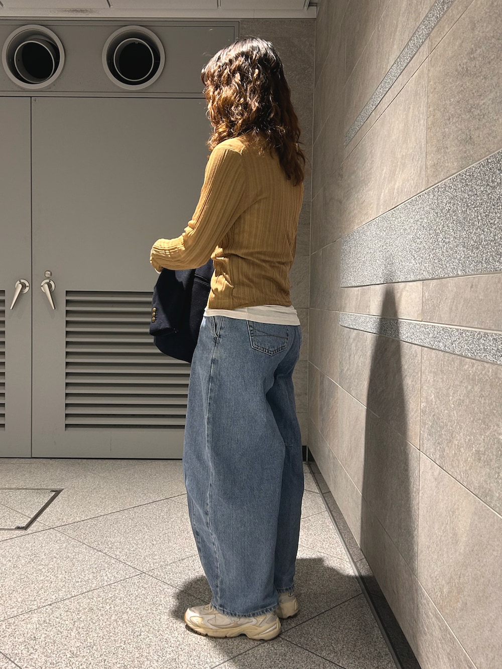 ベージュ系のトップス、ブルー系のテーラードジャケット、ブルー系のデニムパンツを着用したレディースの春コーディネートの5枚目の写真