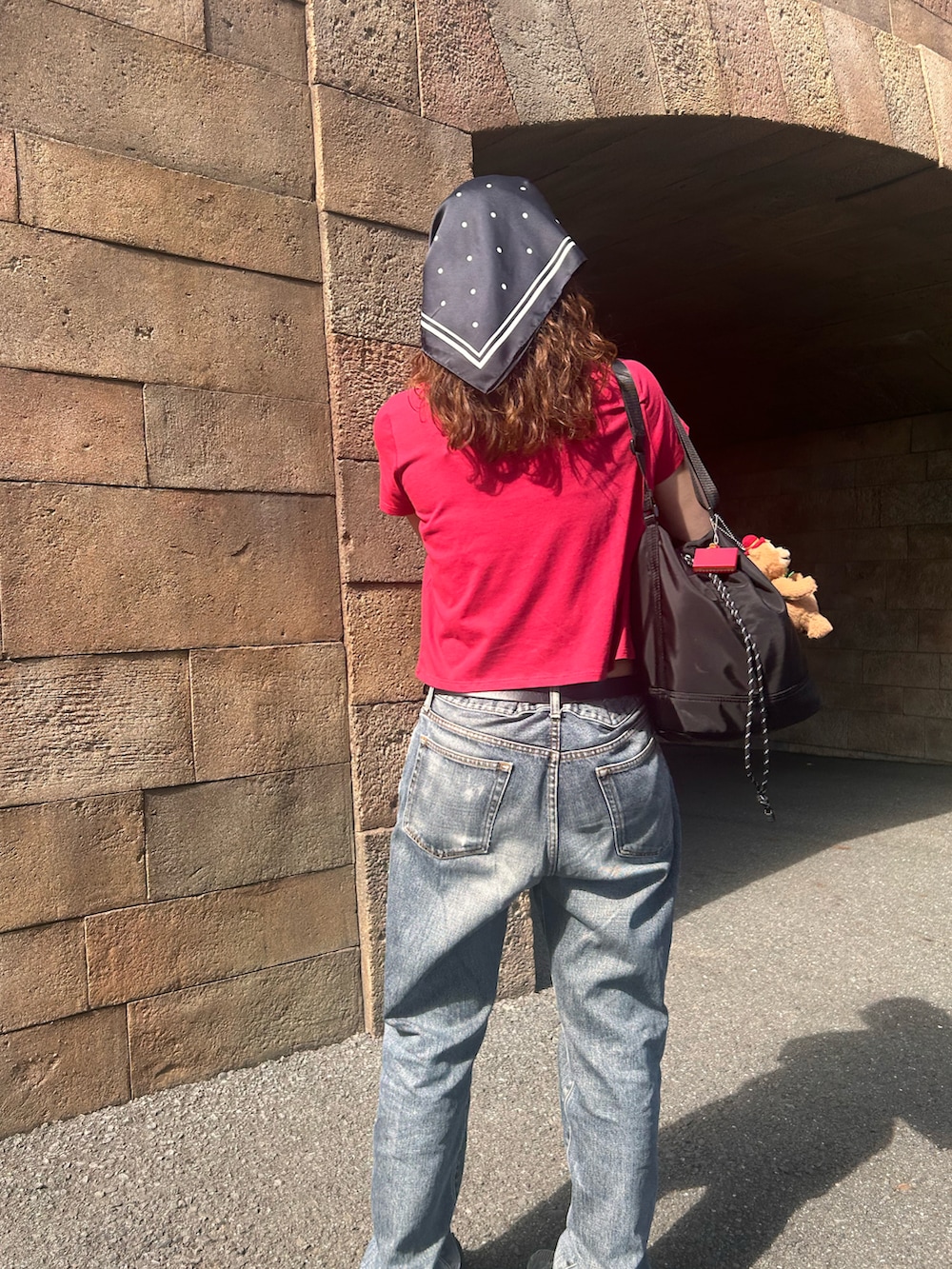 レッド系のTシャツ/カットソー、ブラック系のスニーカー、ブラック系のデニムパンツを着用したレディースの春コーディネートの3枚目の写真