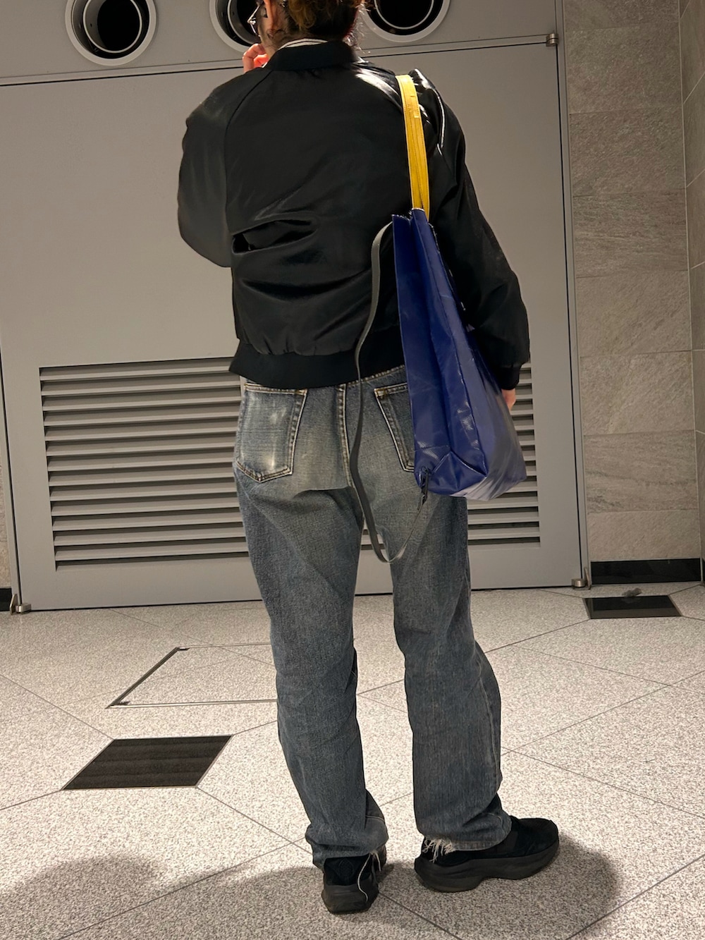 ブラック系のスニーカー、ブラック系のブルゾン、ブラック系のデニムパンツを着用したレディースの春コーディネートの4枚目の写真