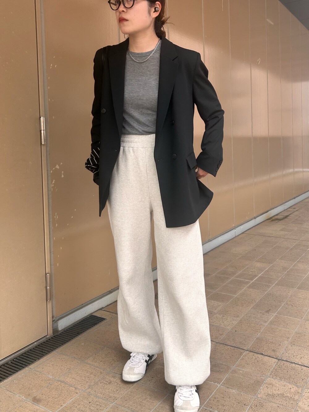 ホワイト系のスニーカー、グレー系のTシャツ/カットソー、ブラック系のテーラードジャケットを着用したレディースの春コーディネートの2枚目の写真